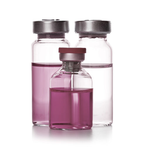 three glass vials containing colored liquids